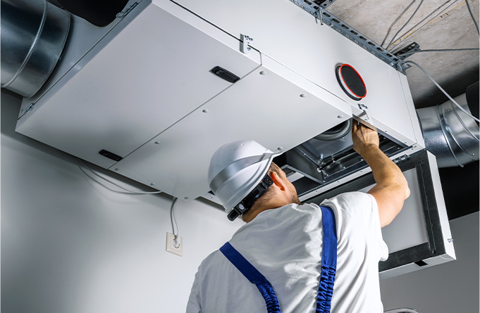 Worker adjusting overhead vent unit.